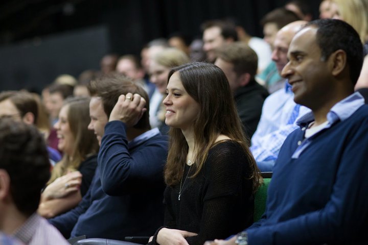 RADA Business course participants watch a presentation in an auditorium.
