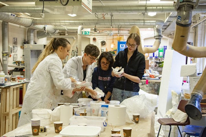 In a busy props workshop at RADA, four theatre production students dip objects in to plaster to cast props for a show
