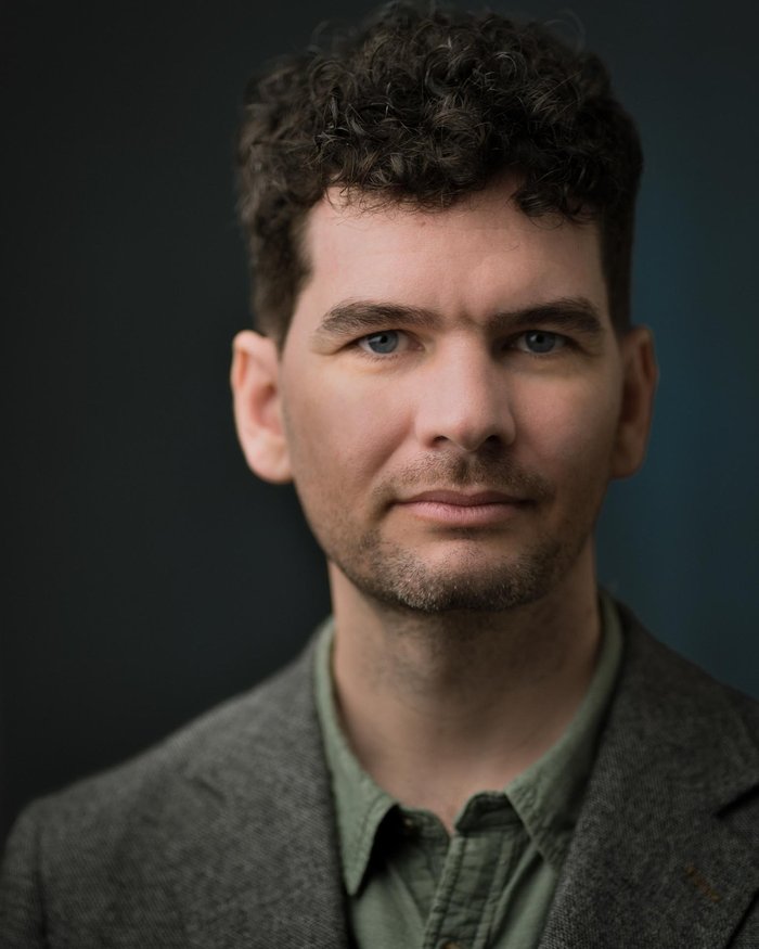Headshot of Anthony Arblaster in a green shit and dark grey wool blazer looking directly into the camera.