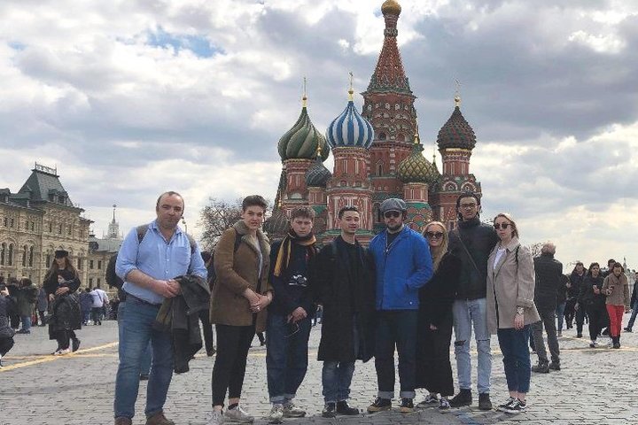 Students and staff from RADA pose smiling in front of St Basil's Cathedral, Red Square, Moscow