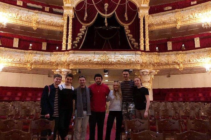 Students and staff from RADA pose smiling in the opulent red and gold Bolshoi Theatre, Moscow