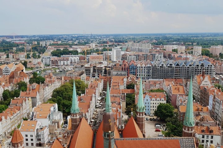 A view of the rooftops of Gdansk in the sunshine, featuring terracotta rooftops and copper green spires