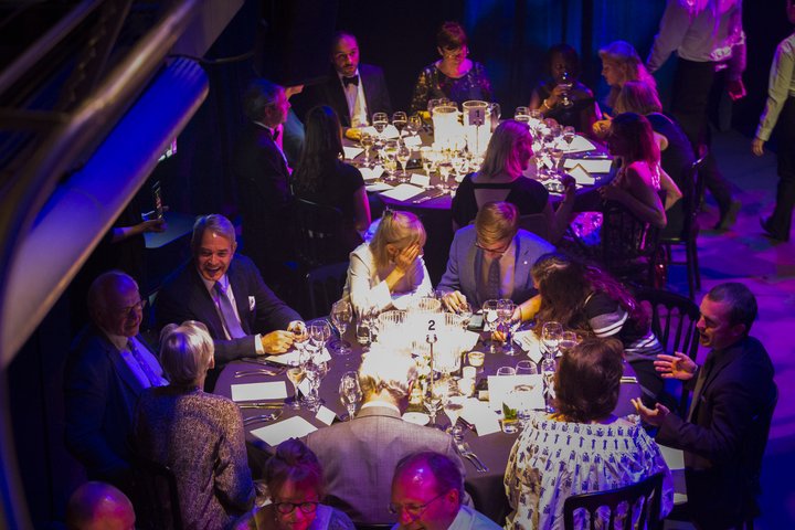 Image of dinner tables and dinner guests set up in RADA's Jerwood Vanbrugh Theatre