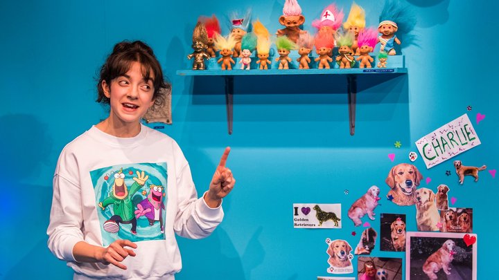 Patsy Ferran gesturing on stage in My Mum's A Tw*t at the Royal Court Theatre; set of a child's bedroom with bright turquoise wall.