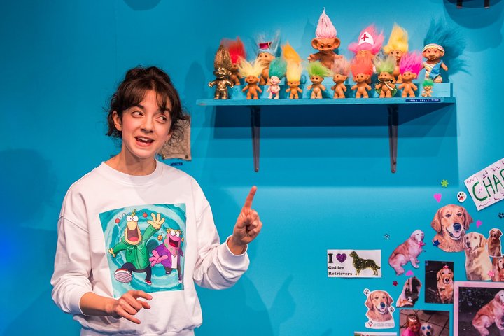 Patsy Ferran gesturing on stage in My Mum's A Tw*t at the Royal Court Theatre; set of a child's bedroom with bright turquoise wall.