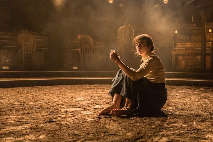 Patsy Ferran sits alone on the floor on stage in the Almeida Theatre's Summer and Smoke in golden light.