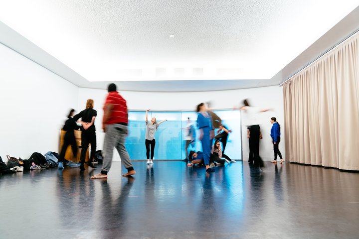 Students rehearse at RADA. They are standing up, making shapes with their arms.