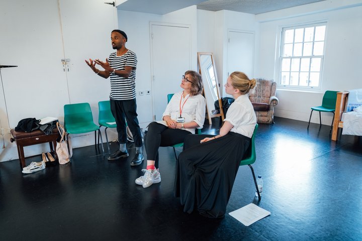 A director gives feedback to two actors.