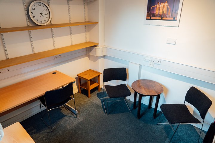 A small, carpeted room with two chairs and a desk.