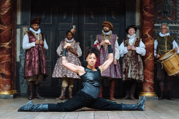 © Helen Murray Actress Stacy Abalogun on stage at the Globe playing a wrestler. She is in the splits with her arms raised above her head, looking strong and powerful