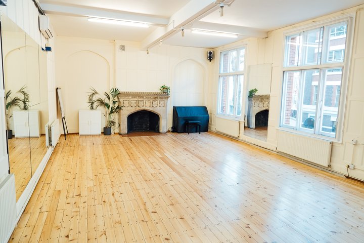 A large rehearsal room with wooden floors.