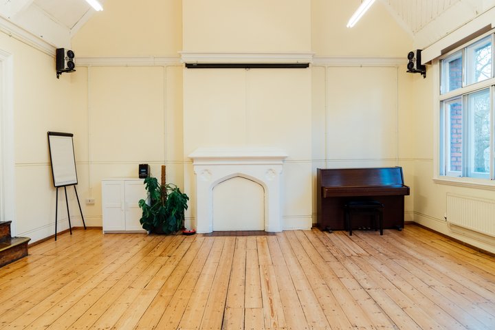 A large rehearsal room with wooden floors.