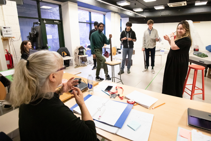 Five actors stood in the Wild Cherries rehearsal room looking at the director who is sat down with her hands in motion.