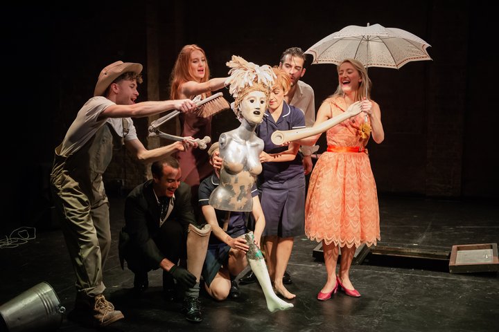 A group of performers gathered around a puppet with costume and props.