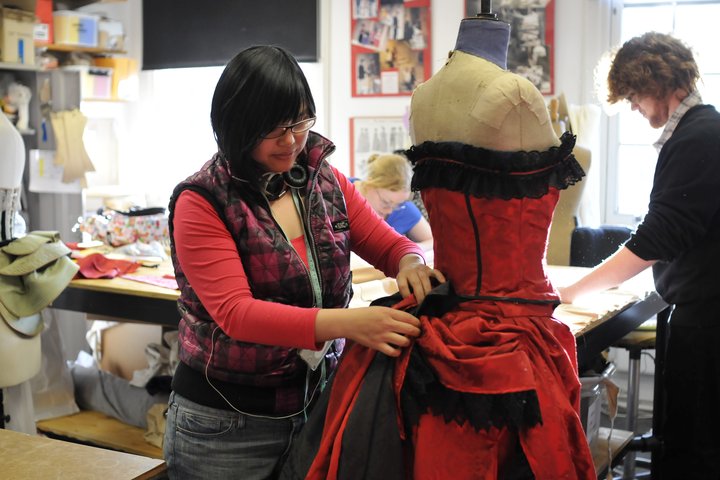 theatre costume student works on a bustle of a Victorian style red dress in the costume workshop