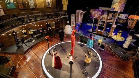 Wide shot of Production Exhibition showing exciting and bright costumes, props, scenic art and construction in an epic theatre setting.