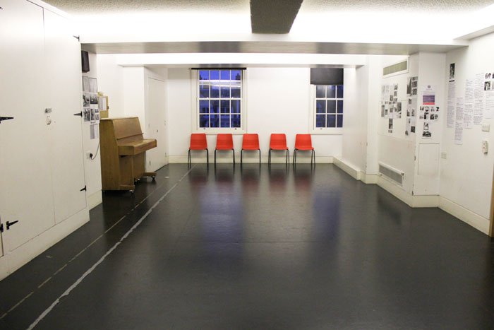 empty Max Reinhardt studio with row of red chairs and upright piano