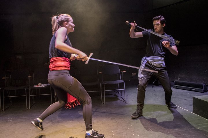 Two students (male and female) practicing stage sword fighting