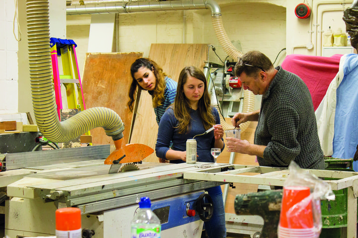 In the props workshop at RADA, a faculty member demonstrates to a female student how to mix liquids for props drinks, while another student looks on