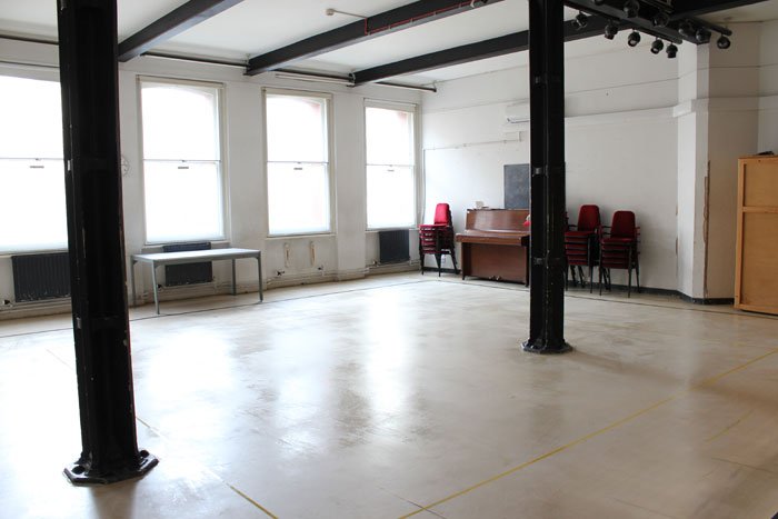 empty Sarah Siddons studio with stacked red chairs and upright piano