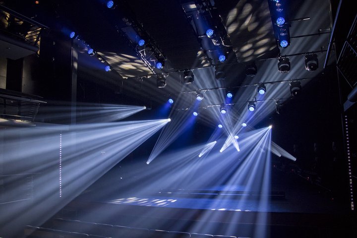 A wide view of the Vanbrugh Theatre stage and auditorium in darkness. Striking blue and white lights shine out across the auditorium and ceiling.