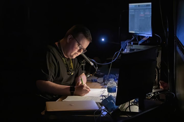 A stage manager works in dark lighting during a performance
