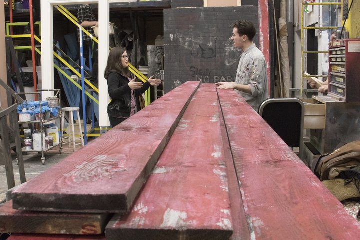 theatre production students talk over planks of wood in scenic art workshop