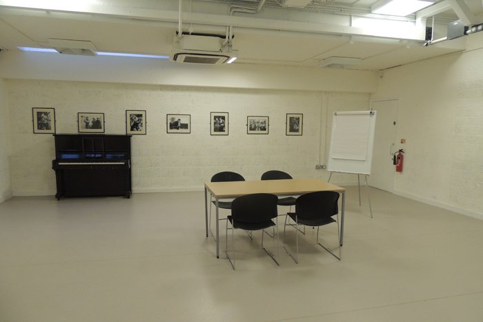 empty training suite studio with table & chairs, flipchart and upright piano